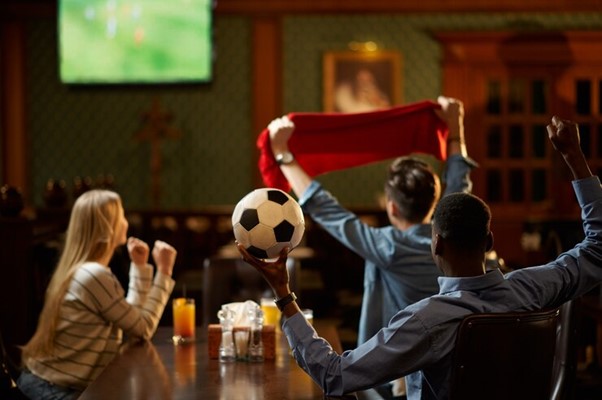 Football fans with red scarf watching game translation, friends in bar
