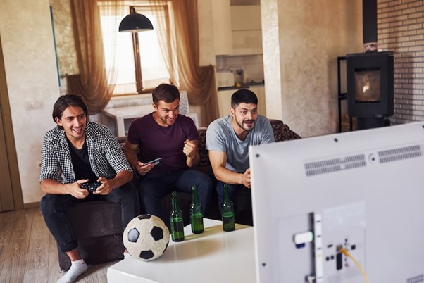Excited three friends watching soccer on TV at home together.